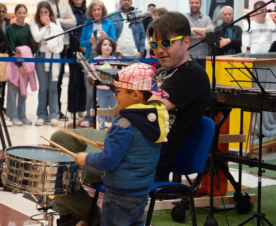 Un bambino del pubblico prova il rullante affiancato da un musicista, al Centro Commerciale L'Aquilone di L'Aquila