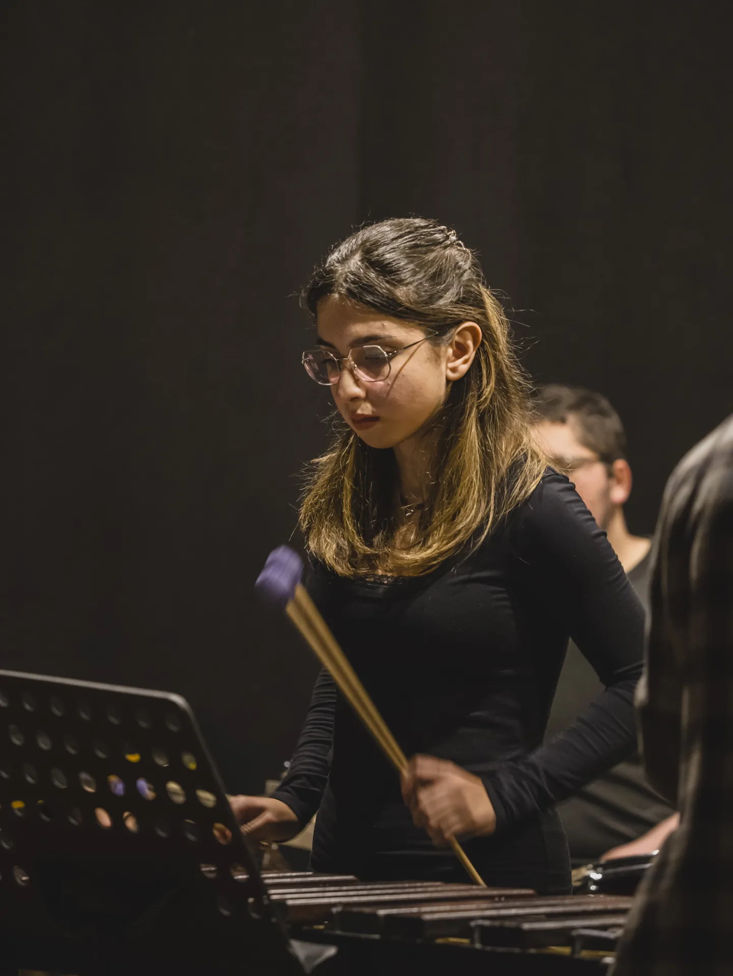 Percussionista con la bacchetta alzata sulla marimba, in primo piano durante il concerto all'Auditorium Cerulli